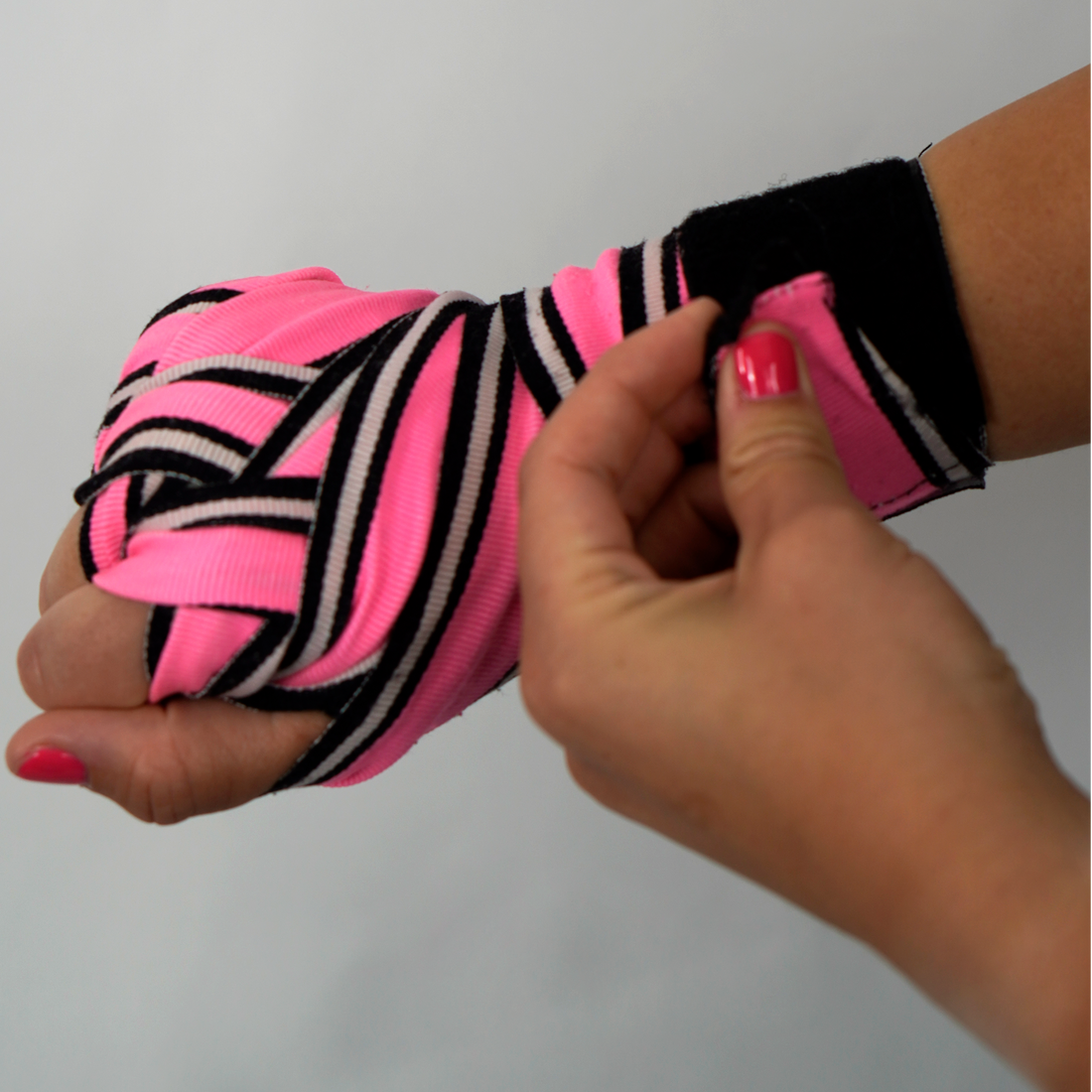 Hand, die in pink-schwarzen Boxbandagen gewickelt ist, wird justiert – Anleitung zum Handbandagieren für Boxen und Kickboxen