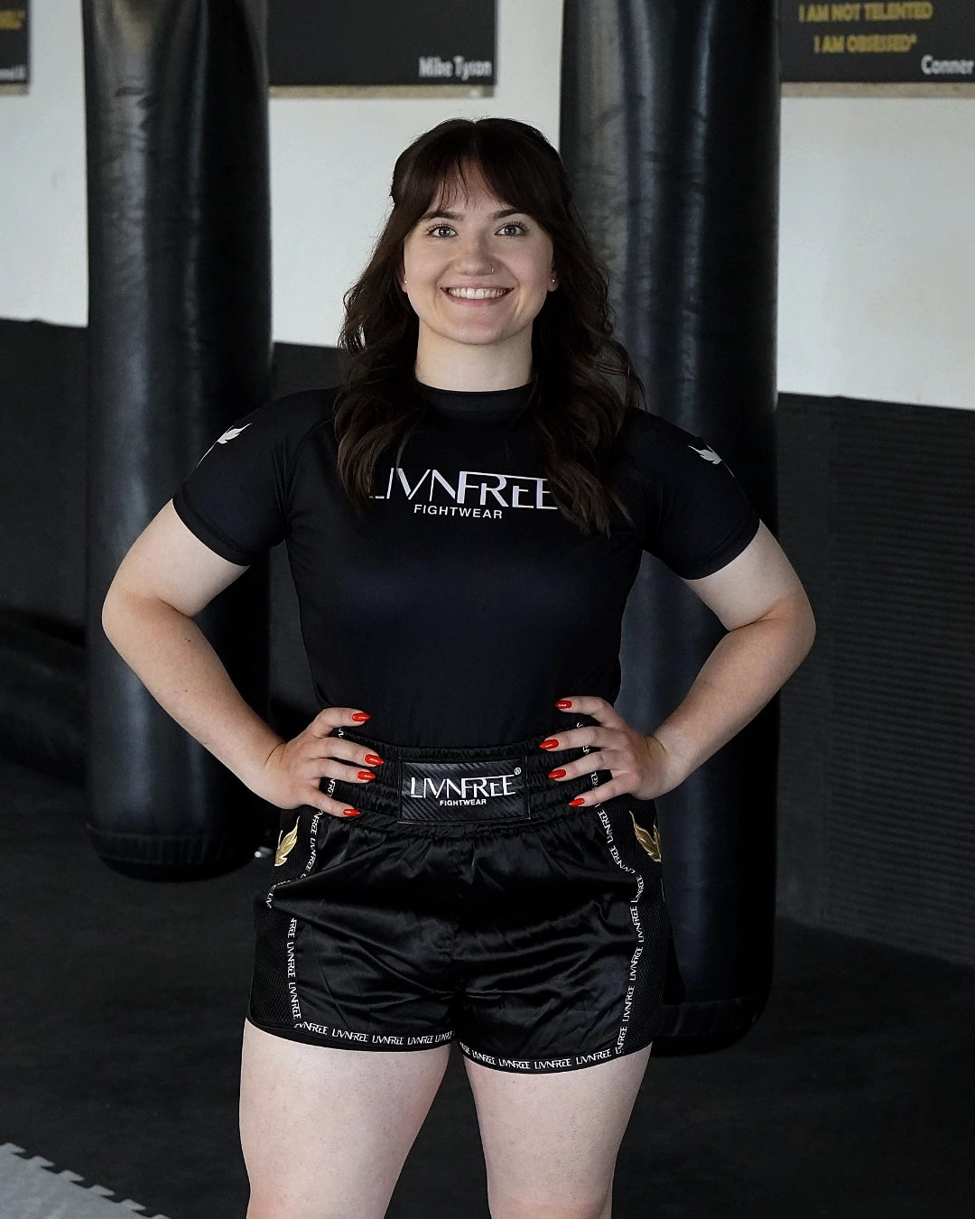 2-in-1 Muay Thai Shorts Damen in Schwarz-Gold, Vorderansicht an Modell im Gym