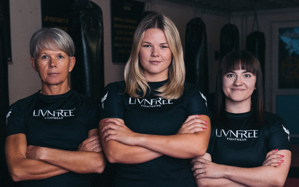 Das Team von Livnfree Fightwear in Kampfsportbekleidung – drei Frauen mit selbstbewusstem Blick und verschränkten Armen in einem Kampfsportkleidung.