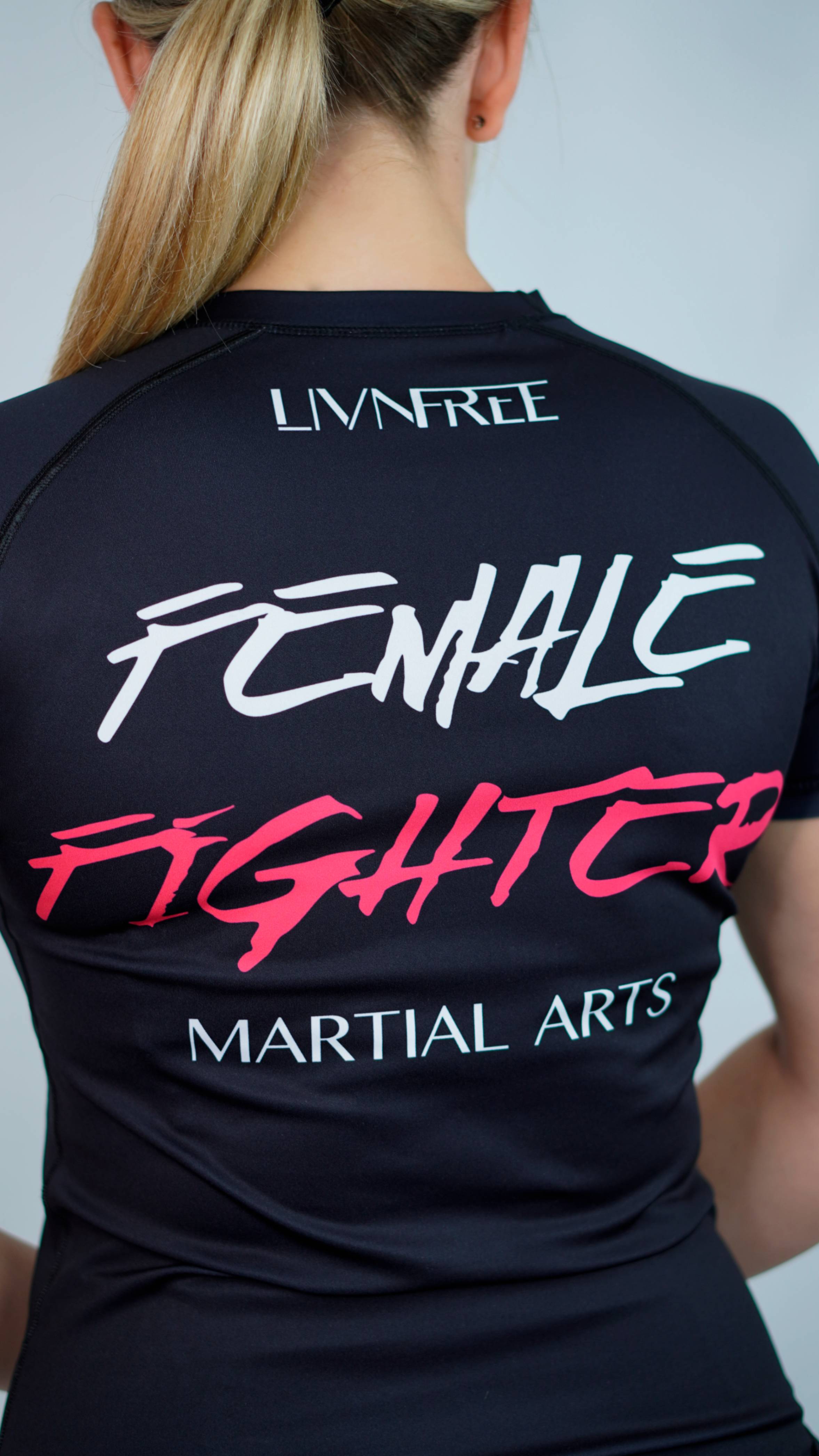 Rückansicht des 'LivnFree'-Rash Guards mit Aufschrift 'Female Fighter - Martial Arts', schwarzes Shirt mit pink-weißem Schriftzug